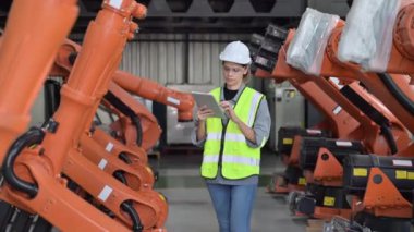 Fabrikada robot makine otomasyonuyla çalışan bakım mühendisi, endüstride akıllı teknolojili kadın teknisyen, robot makinenin parçalarını kontrol eden ve kontrol eden kadın işçi.