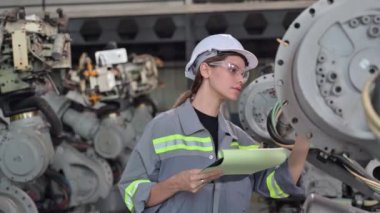 Fabrikada robot makine otomasyonuyla çalışan bakım mühendisi, endüstride akıllı teknolojili kadın teknisyen, robot makinenin parçalarını kontrol eden ve kontrol eden kadın işçi.