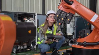 Fabrikada robot makine otomasyonuyla çalışan bakım mühendisi, endüstride akıllı teknolojili kadın teknisyen, robot makinenin parçalarını kontrol eden ve kontrol eden kadın işçi.