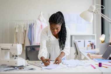Mutlu terzi tasarımcısı atölyede çalışıyor, kadın terzi moda tasarımcısı ölçüleri ve kıyafet provalarını kontrol ediyor, manken giyimi atölyesinde terzilik yapıyor, küçük işletme sahibi.