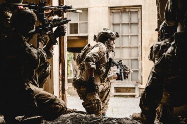 Uzman askerler askeri harekat sırasında düşmana saldırıyor. Koruyucu savaş üniformalı askerler, savaş meydanında tüfekli askerler.