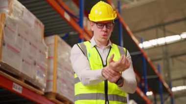 Hardworking male warehouse engineer suffering from hand injury during working at warehouse factory