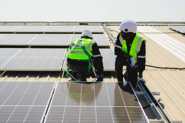 Güneş enerjisi tarlasında güvenlik kaskı olan profesyonel mühendisler, enerji fabrikasının çatısında güneş pili olan teknisyenler, sürdürülebilir kaynak kavramı