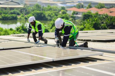 Güneş enerjisi tarlasında güvenlik kaskı olan profesyonel mühendisler, enerji fabrikasının çatısında güneş pili olan teknisyenler, sürdürülebilir kaynak kavramı