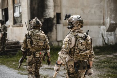 Uzman askerler askeri harekat sırasında düşmana saldırıyor. Koruyucu savaş üniformalı askerler, savaş meydanında tüfekli askerler.