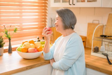 son sınıf fotoğrafı. Neşeli yaşlı gülümseme portresi. Meyve yiyen olgun bir kadın. Yüksek kalite fotoğraf