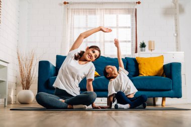 Genç anne ve kızı evde oturma odasında egzersiz yapıyor sağlıklı ve sağlıklı bir aile evde yoga egzersizi yapıyor evde birlikte oynuyorlar sağlıklı yaşam tarzına sahip bir aile.