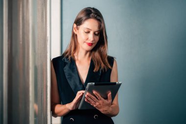 Şirkette tablet kullanan güzel bir iş kadını, modern ofiste çalışan bir kadın, yaratıcı ofiste çalışan şık giyinen bir kadın.