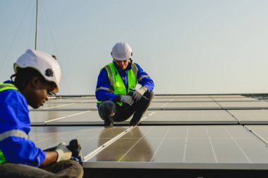 Güneş pili çiftliğine güneş panelleri kuran bakım teknisyenleri, elektrik santralinde çalışan mühendisler, güneş panelleri alanında elektrik sistemi bakımı, çevre dostu ve temiz enerji