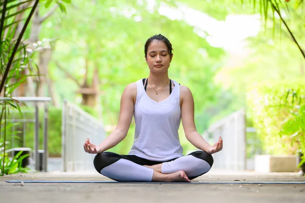 stock image Healthy young woman enjoying and relaxing yoga outdoor in green park, Woman doing yoga exercise outdoor with happiness, Positive fit woman practicing yoga on open air outside in morning