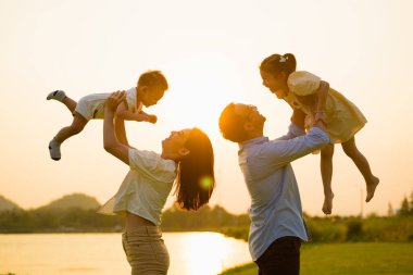 Anne ve baba, akşamları birlikte parkta oynayan çocukları, neşeli aile manzarasını, anne ve çocukları parkta pikniği, sağlıklı yaşam tarzını,