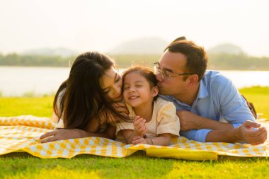 Mutlu bir aile hafta sonu parkta dinleniyor ve dinleniyor, aile babası ve kızı parkta piknik yapıyor, ebeveynler kızlarıyla seyahat ediyor, aile hayatı sürüyor. 