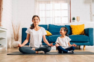 Genç anne ve kızı evde oturma odasında egzersiz yapıyor sağlıklı ve sağlıklı bir aile evde yoga egzersizi yapıyor evde birlikte oynuyorlar sağlıklı yaşam tarzına sahip bir aile.