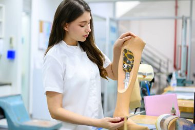 Protez uzuv kontrolü yapan ve laboratuvarda çalışan kadın teknisyen, protez üretiminde yüksek teknoloji uzmanı, engelliler için yeni yapay uzuv üretimi