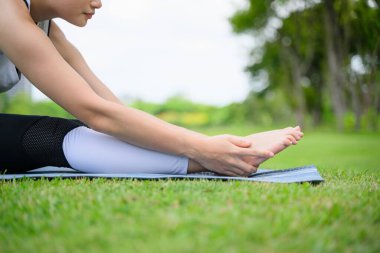 Sağlıklı genç bir kadın, yeşil parkta yoga yaparken ve dinlenirken, yoga yaparken, dışarıda mutlulukla, sağlıklı bir kadın, sabahları, açık havada yoga yaparken,
