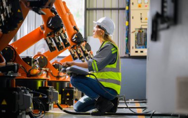 Fabrikada robot makine otomasyonuyla çalışan kadın mühendis endüstride akıllı teknolojili kadın teknisyen, robot makinenin parçalarını kontrol eden ve kontrol eden kadın işçi.