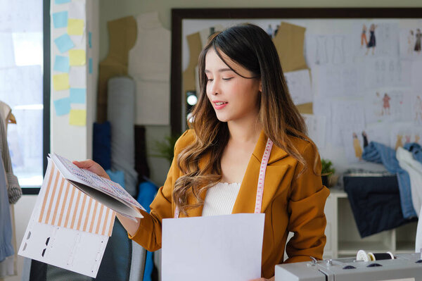 Female fashion designer woman working on her designs in workshop studio, Female business owner with clothes, Tailoring business owner, Clothing store owner, Design fashion clothes by designer. High