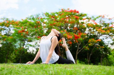 Sağlıklı genç bir kadın, yeşil parkta yoga yaparken ve dinlenirken, yoga yaparken, dışarıda mutlulukla, sağlıklı bir kadın, sabahları, açık havada yoga yaparken,