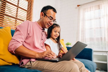 Babam kızıyla oturma odasında oynarken dizüstü bilgisayar kullanıyor mutlu bir aile evde oynarken mutlu bir aile.