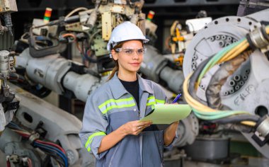 Fabrikada robot makine otomasyonuyla çalışan kadın mühendis endüstride akıllı teknolojili kadın teknisyen, robot makinenin parçalarını kontrol eden ve kontrol eden kadın işçi.