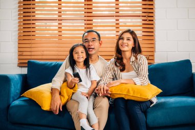 Mutlu bir aile oturma odasında birlikte televizyon izliyor, anne ve baba evde eğleniyor, aile oturma odasında rahat bir koltukta oturuyor, aile hayatı yaşıyor.