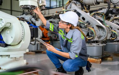 Fabrikada robot makine otomasyonuyla çalışan kadın mühendis endüstride akıllı teknolojili kadın teknisyen, robot makinenin parçalarını kontrol eden ve kontrol eden kadın işçi.