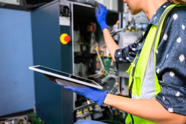 Endüstriyel fabrikada çalışan profesyonel kadın işyeri mühendisi, otomasyon teknolojisi fabrikasında robot makinesini kontrol eden kadın mühendis.