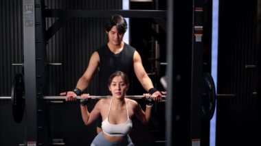 Modern spor salonunda egzersiz yapan iki erkek ve kadın, aktif kas sporcuları, spor salonunda spor yapan insanlar, ağırlık kaldıran güçlü insanlar, ağırlık kaldıran halterler, vücut geliştirme egzersizleri.