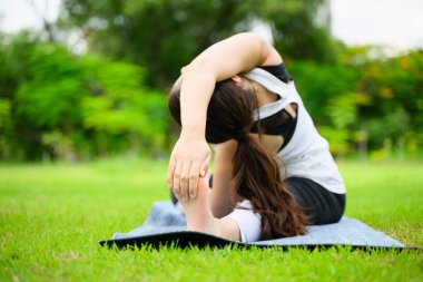 Sağlıklı genç bir kadın, yeşil parkta yoga yaparken ve dinlenirken, yoga yaparken, dışarıda mutlulukla, sağlıklı bir kadın, sabahları, açık havada yoga yaparken,