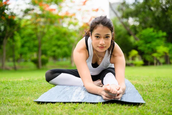 Sağlıklı genç bir kadın, yeşil parkta yoga yaparken ve dinlenirken, yoga yaparken, dışarıda mutlulukla, sağlıklı bir kadın, sabahları, açık havada yoga yaparken,