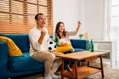 Televizyonda birlikte maç izleyen mutlu karı koca, oturma odasında tezahürat yapan ve bağıran insanlar, evdeki aktivitelerle eğlenen aileler.