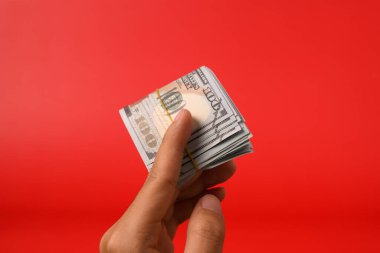 Kırmızı arka planda 100 dolarlık banknotlar, para biriktirmek için banknotlar, nakit para dolarları, iş yatırımları ve gelir, küresel mali kriz, kazanç ve tasarruf konsepti. Yüksek