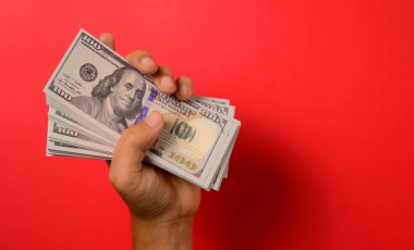 Kırmızı arka planda yüz dolarlık banknotlar, para tasarrufu için banknotlar, nakit para dolarları, iş yatırımları ve gelir, küresel mali kriz, kazanç ve tasarruf para konsepti. Yüksek kalite fotoğraf