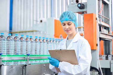 Şişeleme fabrikası işçisi sevkiyattan önce su şişelerinin kalitesini kontrol ediyor. Bitkide kullanılan ters osmoz sistemi. Su saflığı ve şişeleme sürecinde kalite kontrolü. Yüksek kalite fotoğraf.