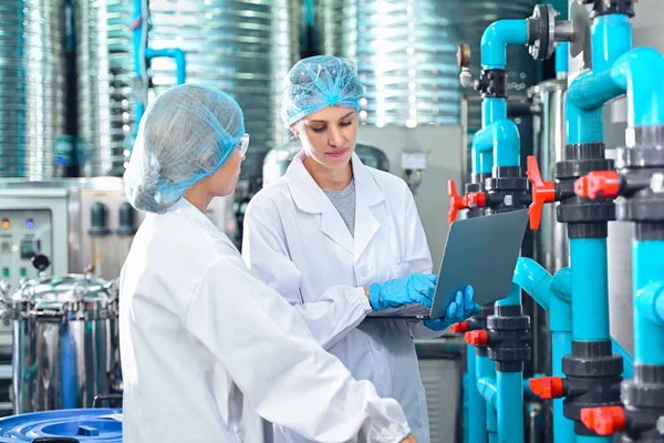 Şişeleme fabrikası işçisi sevkiyattan önce su şişelerinin kalitesini kontrol ediyor. Bitkide kullanılan ters osmoz sistemi. Su saflığı ve şişeleme sürecinde kalite kontrolü. Yüksek kalite fotoğraf.