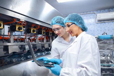 Şişeleme fabrikası işçisi sevkiyattan önce su şişelerinin kalitesini kontrol ediyor. Bitkide kullanılan ters osmoz sistemi. Su saflığı ve şişeleme sürecinde kalite kontrolü. Yüksek kalite fotoğraf.