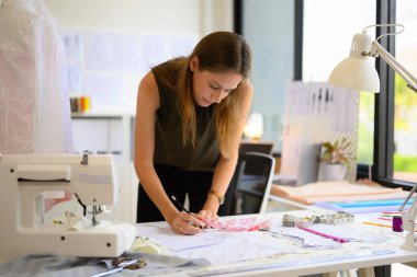 Atölyede çalışan güzel kadın terzi, kadın terzi ölçü ve kıyafet provaları, manken giyimi atölyesinde terzilik, küçük işletme sahibi.