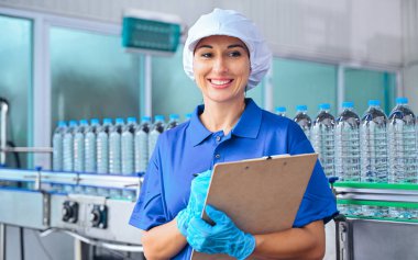 Şişeleme fabrikası işçisi sevkiyattan önce su şişelerinin kalitesini kontrol ediyor. Bitkide kullanılan ters osmoz sistemi. Su saflığı ve şişeleme sürecinde kalite kontrolü. Yüksek kalite fotoğraf.