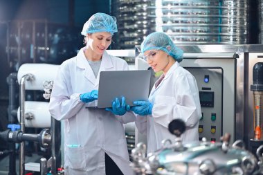 Şişeleme fabrikası işçisi sevkiyattan önce su şişelerinin kalitesini kontrol ediyor. Bitkide kullanılan ters osmoz sistemi. Su saflığı ve şişeleme sürecinde kalite kontrolü. Yüksek kalite fotoğraf.