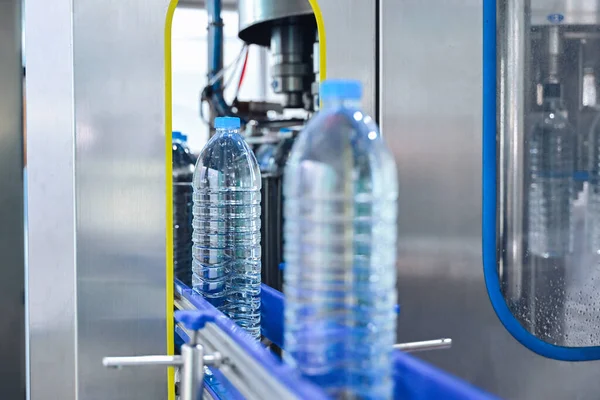 Bottling factory worker inspecting quality of water bottles before shipment. Reverse osmosis system used in plant. water purity and maintaining quality control in bottling process. High quality photo.