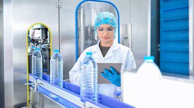 Şişeleme fabrikası işçisi sevkiyattan önce su şişelerinin kalitesini kontrol ediyor. Bitkide kullanılan ters osmoz sistemi. Su saflığı ve şişeleme sürecinde kalite kontrolü. Yüksek kalite fotoğraf.