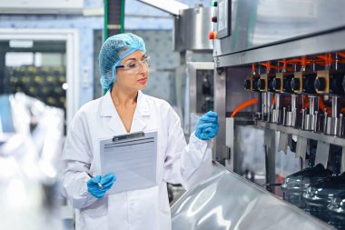 Şişeleme fabrikası işçisi sevkiyattan önce su şişelerinin kalitesini kontrol ediyor. Bitkide kullanılan ters osmoz sistemi. Su saflığı ve şişeleme sürecinde kalite kontrolü. Yüksek kalite fotoğraf.