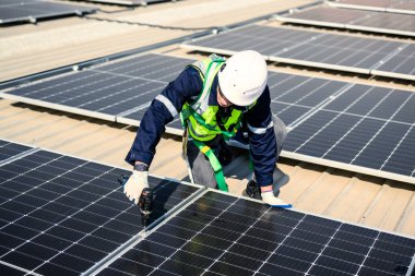 Güneş enerjisi tarlasında güvenlik kaskı olan profesyonel mühendisler, enerji fabrikasının çatısında güneş pili olan teknisyenler, sürdürülebilir kaynak kavramı