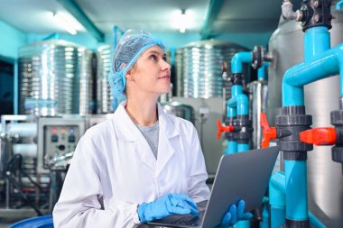 Şişeleme fabrikası işçisi sevkiyattan önce su şişelerinin kalitesini kontrol ediyor. Bitkide kullanılan ters osmoz sistemi. Su saflığı ve şişeleme sürecinde kalite kontrolü. Yüksek kalite fotoğraf.