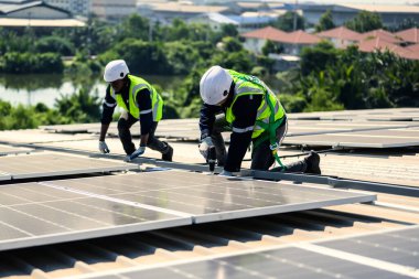 Güneş enerjisi tarlasında güvenlik kaskı olan profesyonel mühendisler, enerji fabrikasının çatısında güneş pili olan teknisyenler, sürdürülebilir kaynak kavramı