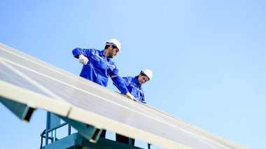Endüstriyel güneş pili çiftliğine güneş panelleri kuran teknisyen ekibi, elektrik santralinde çalışan mühendisler, güneş panelleri alanında elektrik sistemi bakımı, çevre dostu ve temiz enerji