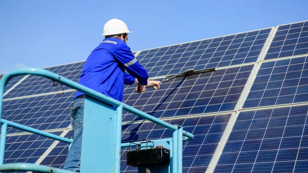Maintenance worker cleaning solar panels at industrial solar cell farm station, People working with alternative energy, Solar energy from sun
