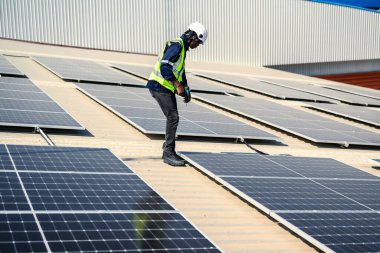 Güneş enerjisi tarlasında güvenlik kaskı olan profesyonel mühendisler, enerji fabrikasının çatısında güneş pili olan teknisyenler, sürdürülebilir kaynak kavramı