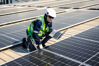 Güneş enerjisi tarlasında güvenlik kaskı olan profesyonel mühendisler, enerji fabrikasının çatısında güneş pili olan teknisyenler, sürdürülebilir kaynak kavramı