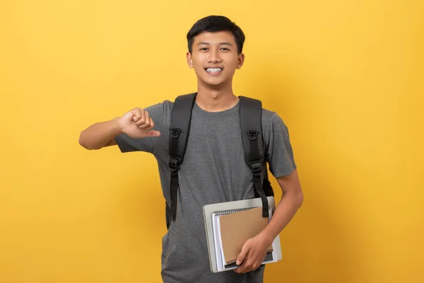 Glimlachende Jonge Student Met Boeken Rugzak Geïsoleerd Gele Achtergrond Wijzend — Stockfoto
